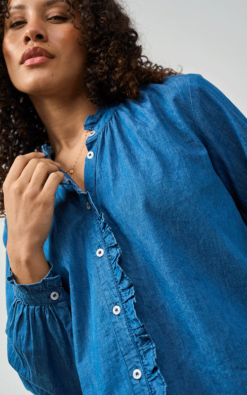Woman wearing Luella Brora soft cotton denim blouse with frilled collar and button cuffs