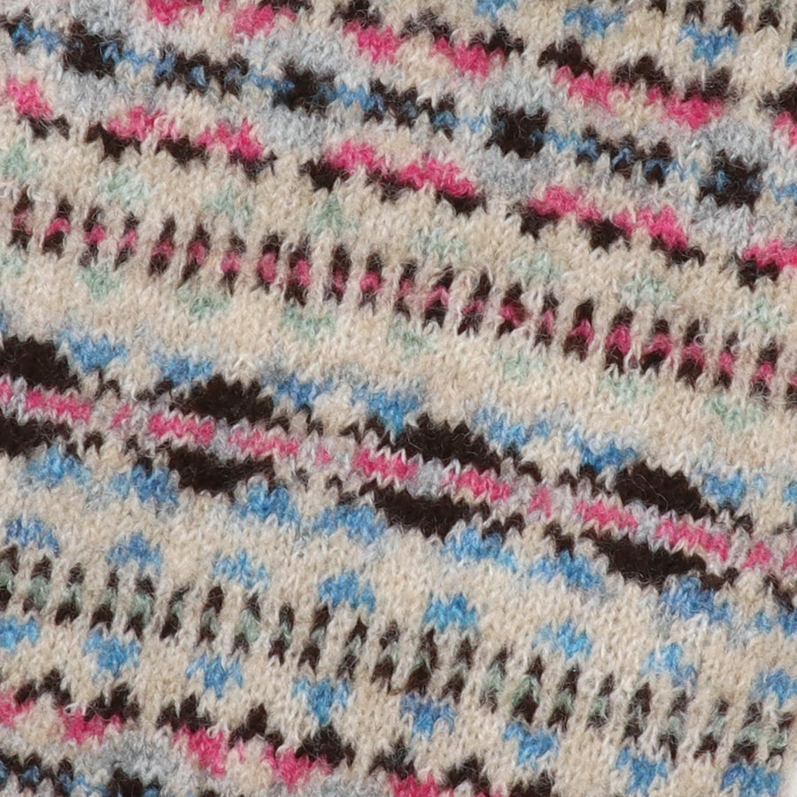 Close-up of the POM Iris hot water bottle fair isle knit cover, showing the intricate pattern in oatmeal, hot pink, cornflower blue, mint and dark brown.