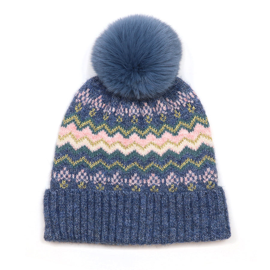 POM Sofia denim and pink Fair Isle bobble hat photographed from the front against a white background, showing the denim blue knit with chevron and diamond Fair Isle pattern in blush pink, teal and gold metallic thread, deep ribbed cuff and fluffy denim blue faux fur pom pom on top.