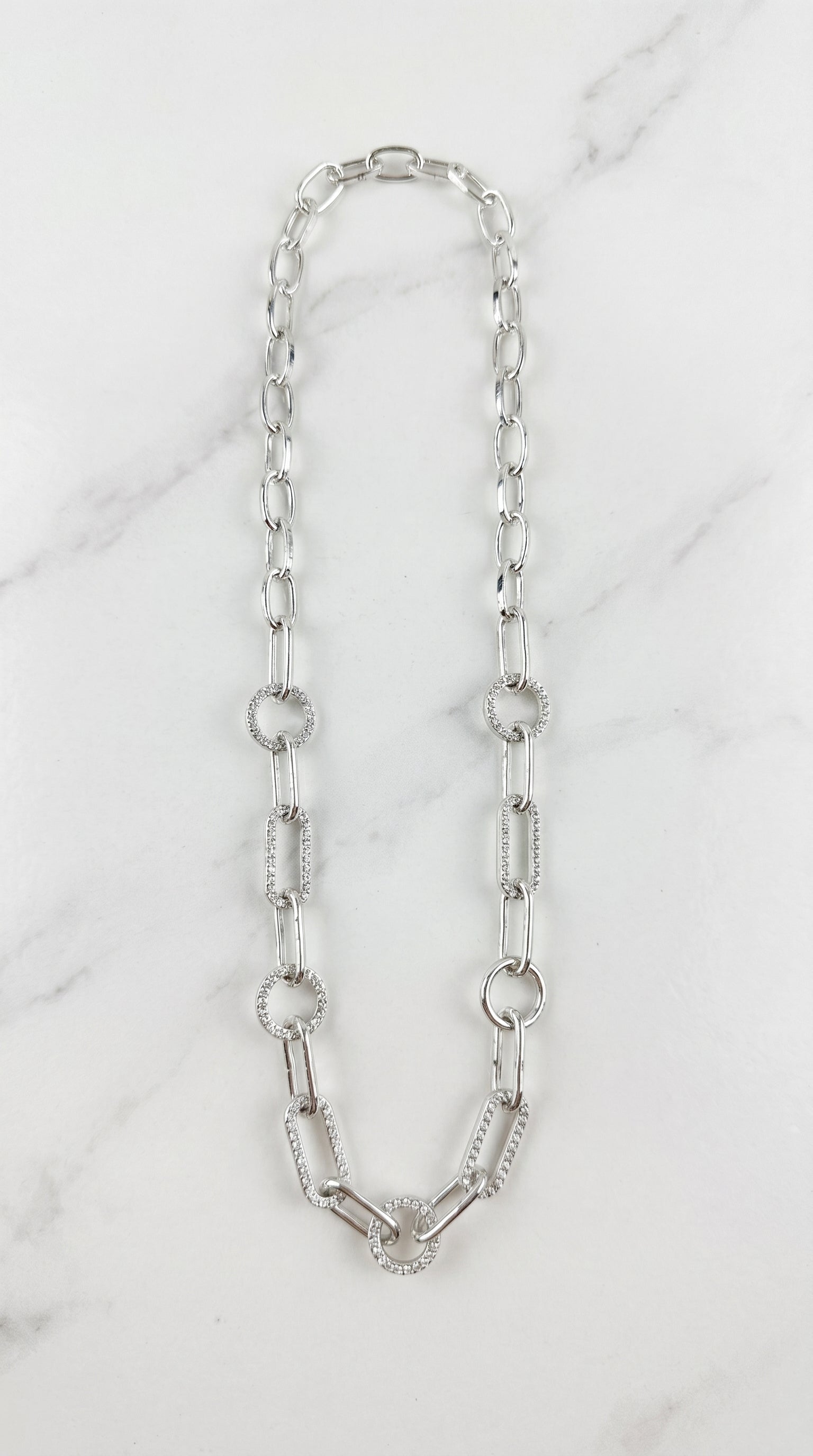 Envy silver-toned chain necklace featuring alternating polished bar links and textured circular links, displayed on a white marble surface.