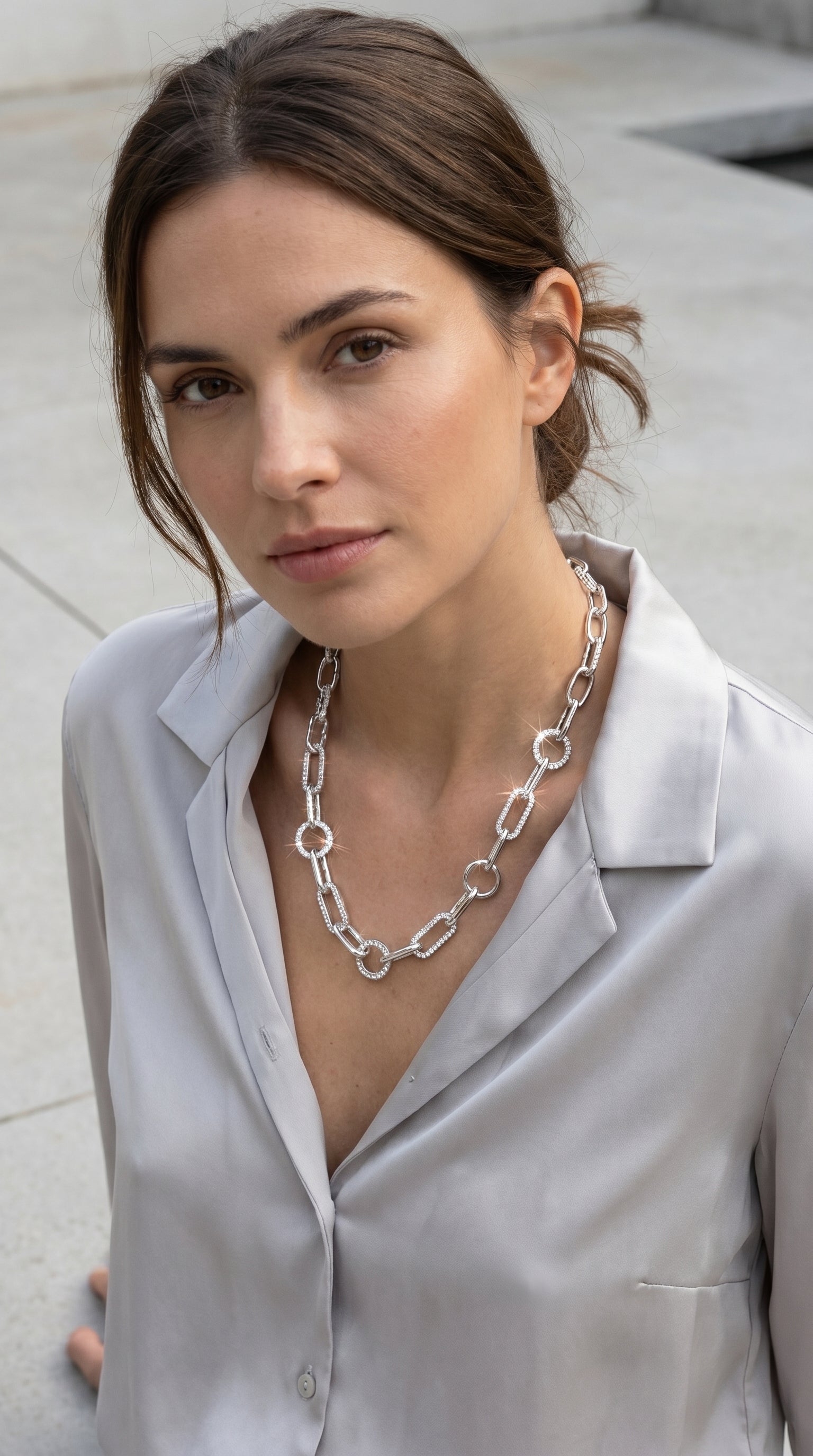 Model wearing Envy silver paperclip and pavé crystal oval link chain necklace with grey satin shirt