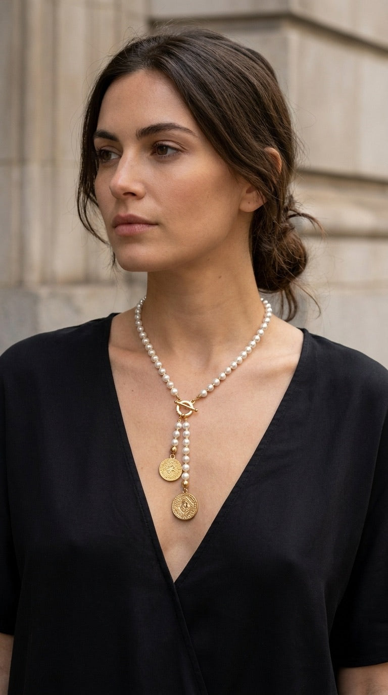 Model wearing Envy pearl and gold coin toggle necklace with black v-neck top