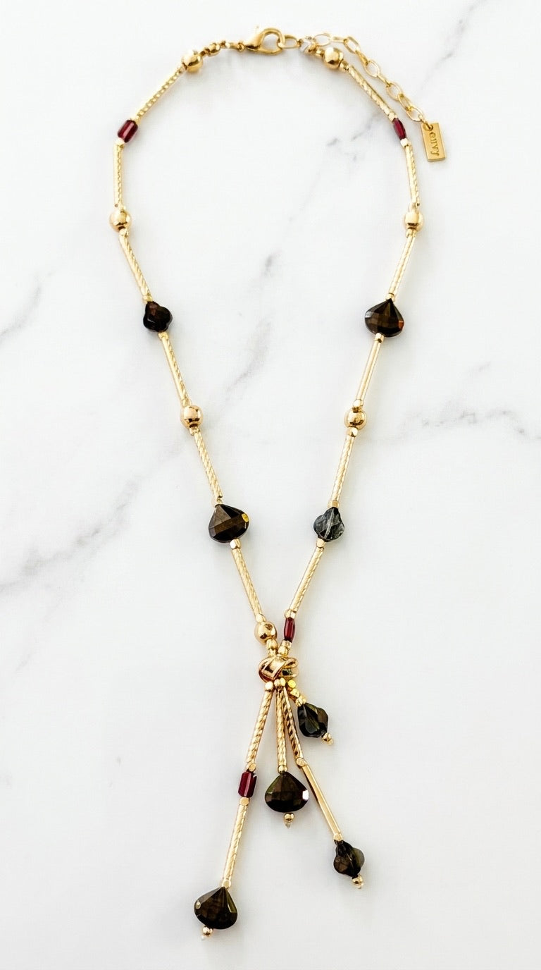 Envy gold lariat necklace with smoky brown and garnet bead chain and triple drop pendant on marble background