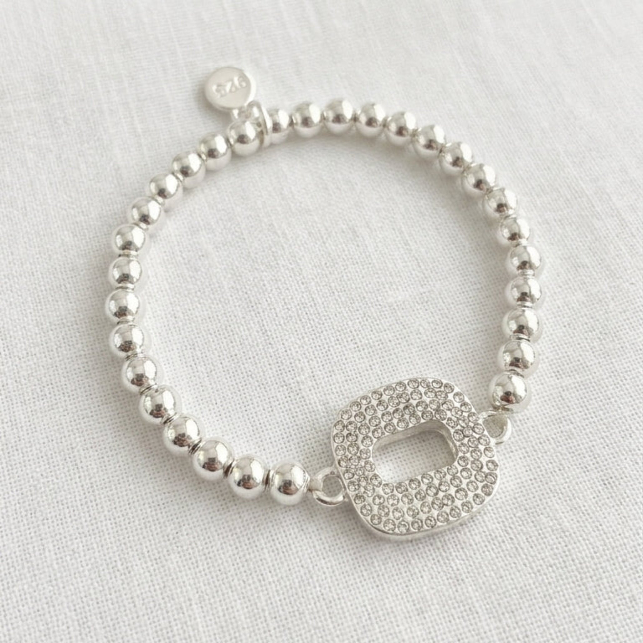Envy silver ball bead stretch bracelet with fully pavé crystal open oval link centrepiece on cream linen background