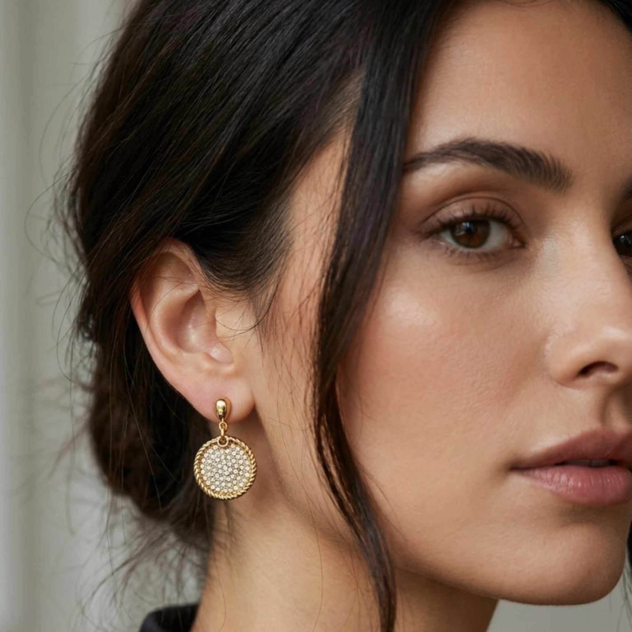 Textured gold earrings with a circular crystal disc charm