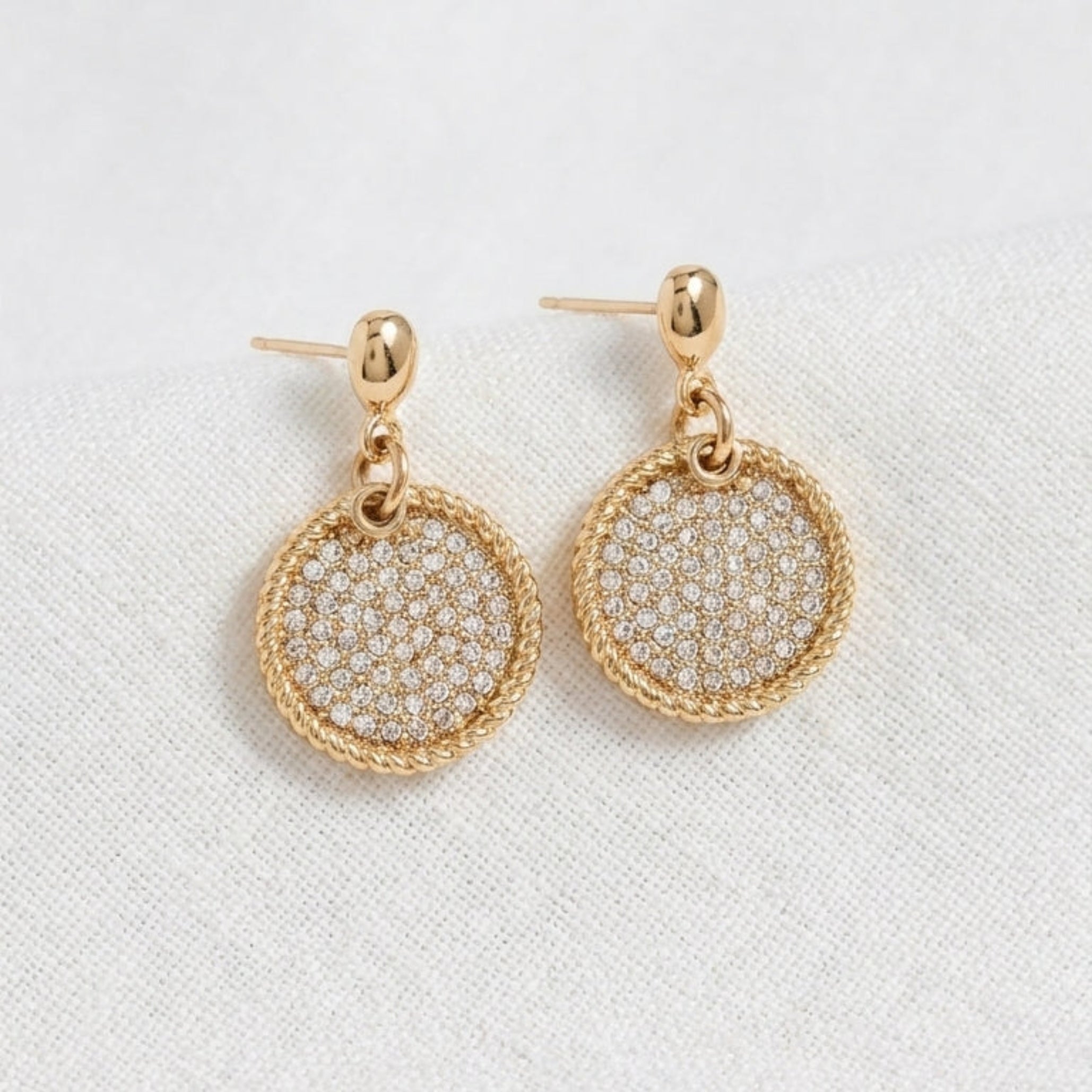 Textured gold earrings with a circular crystal disc charm