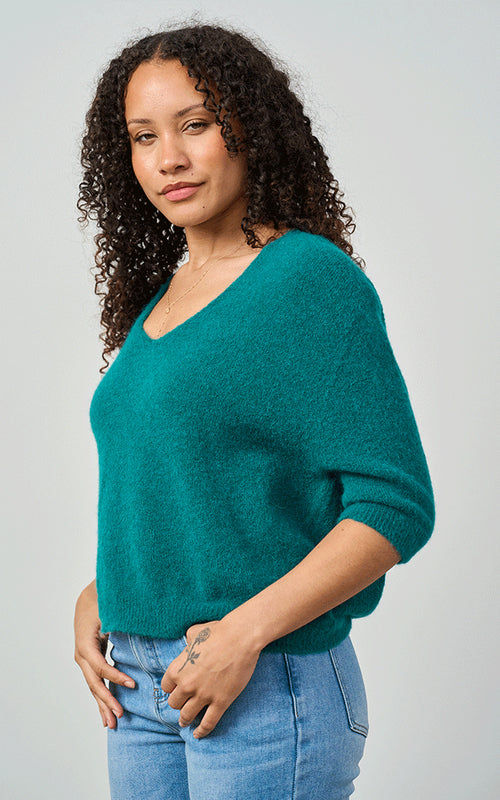 Woman wearing Luella Valentina teal alpaca short-sleeve V-neck knit jumper with blue jeans