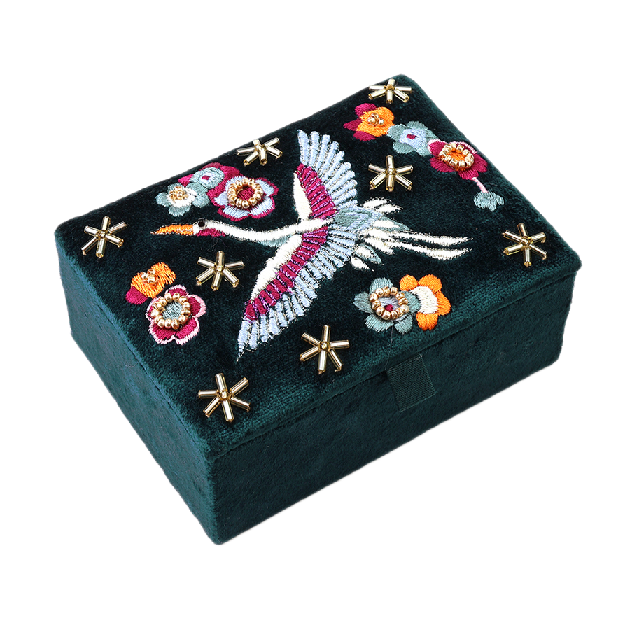 POM Crane teal velvet jewellery box with hand-embroidered soaring crane, vivid red, orange and sage blooms and gold star beads on the lid, shown closed against a white background.