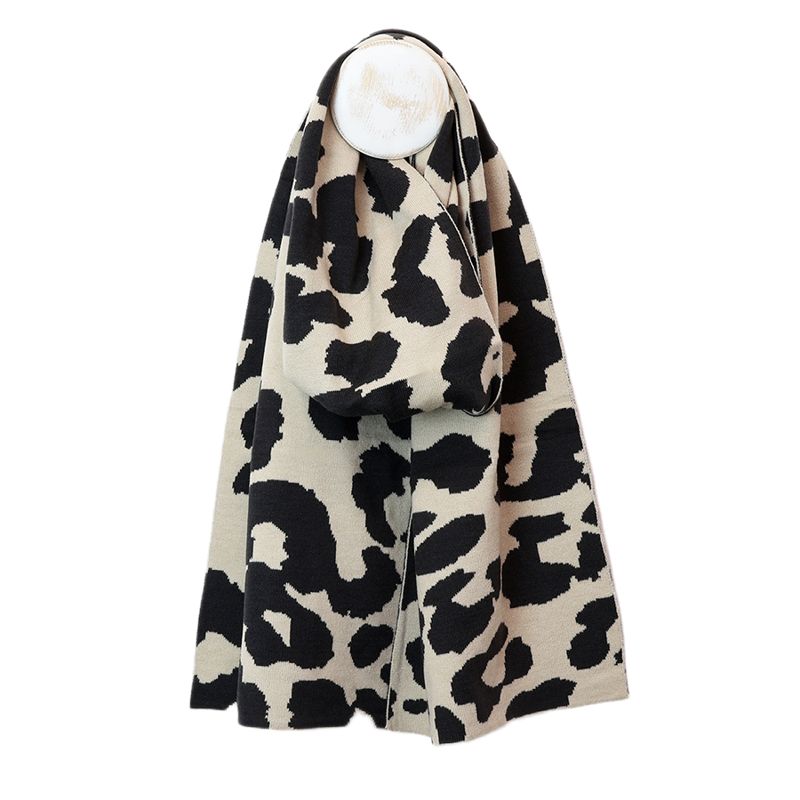 POM Carly oatmeal and black oversized leopard print knitted scarf draped on a mannequin stand against a white background, showing the bold all-over animal print and generous length.