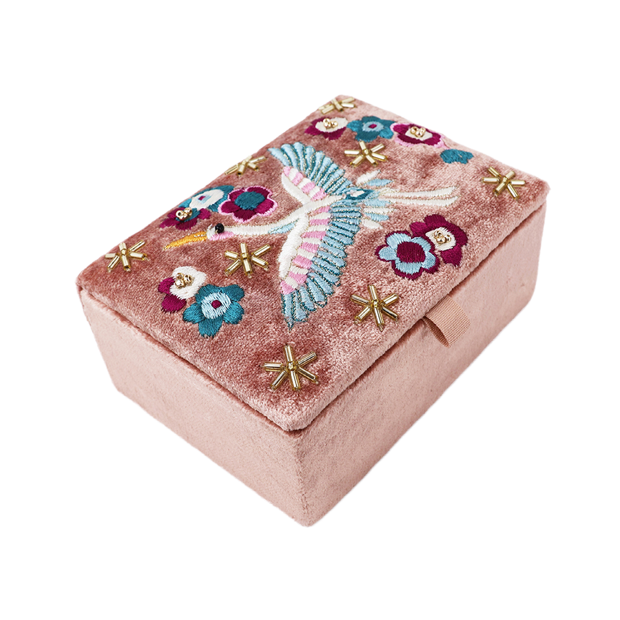 POM Crane blush velvet jewellery box shown at an angle closed, displaying the full embroidered crane, teal and burgundy floral design and gold star bead detail across the blush velvet lid.