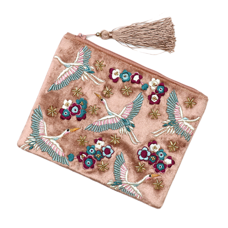 POM Crane blush velvet zip purse shown at an angle, displaying the full hand-embroidered crane, bloom and gold star bead design across the soft blush velvet with gold zip and blush silk tassel pull.