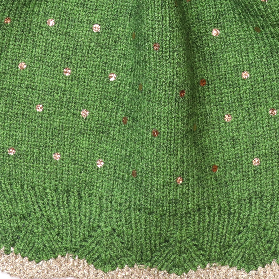 Close-up of the POM Yasmin green knitted pull-through scarf fabric, showing the scattered gold and rose gold metallic sequin spots on the soft ribbed knit with gold lurex trim at the edge.