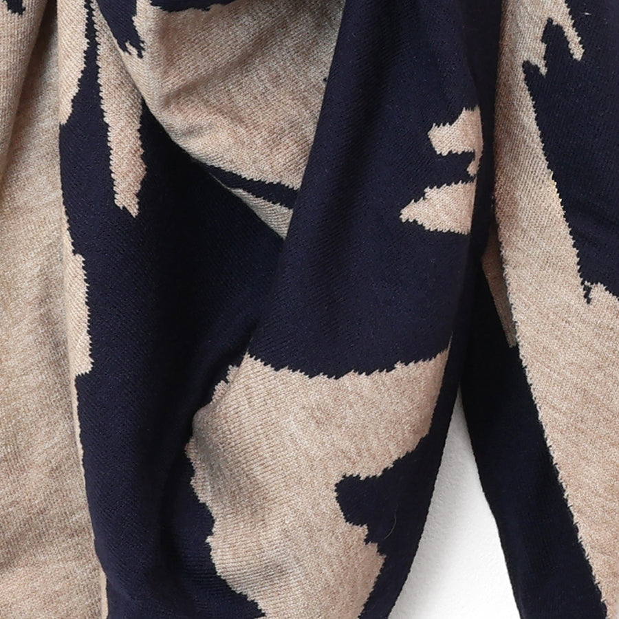 Close-up of the POM navy and oatmeal triangle scarf fabric, showing the soft knit texture and bold abstract animal print pattern in navy and warm oatmeal tones.
