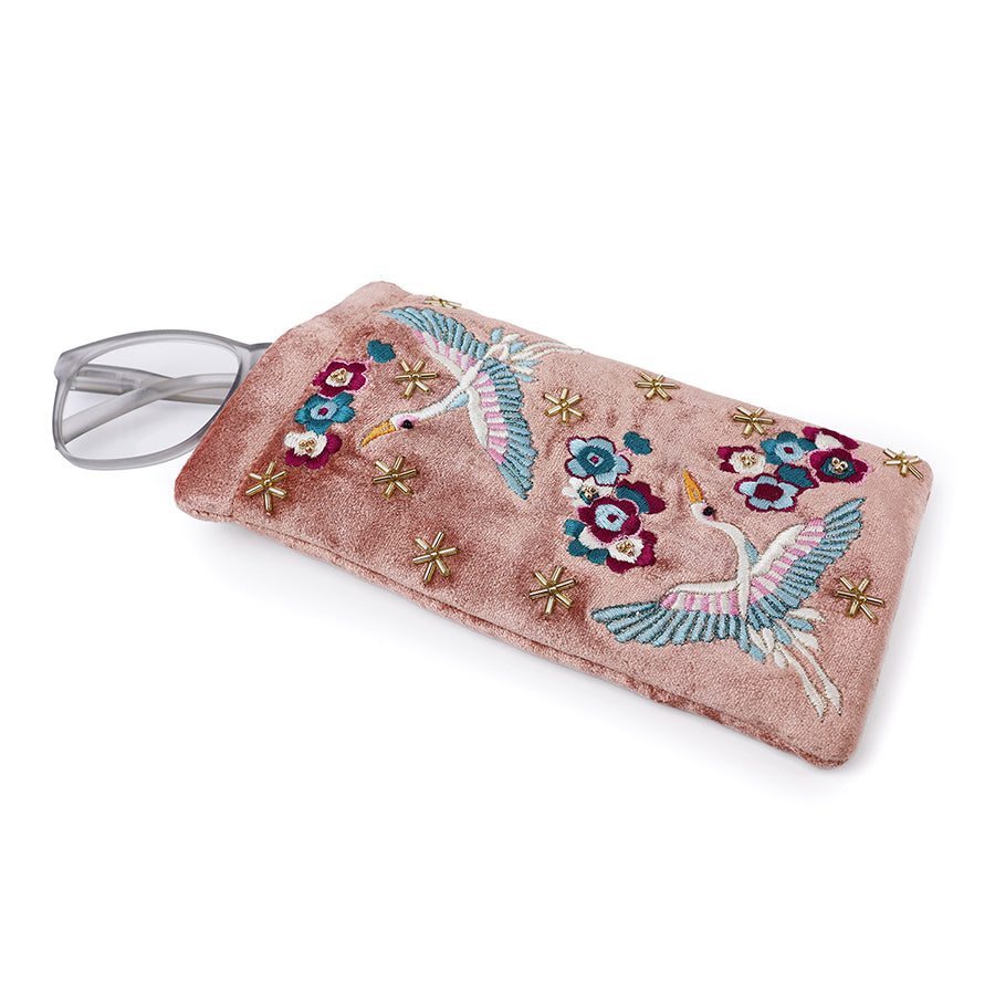 POM Crane blush velvet embroidered glasses case shown open with grey glasses partially inserted, displaying the crane and floral embroidery with gold star bead detail on blush velvet.