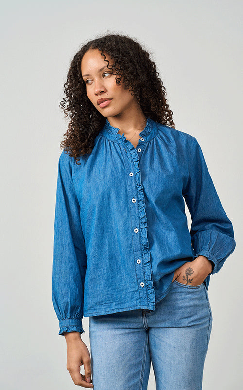 Woman wearing Luella Brora soft cotton denim blouse with frilled collar and button cuffs