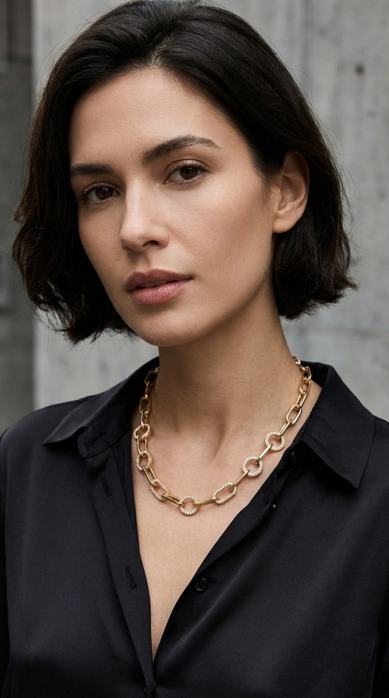 Model wearing Envy gold paperclip and pavé crystal oval link chain necklace with black satin shirt