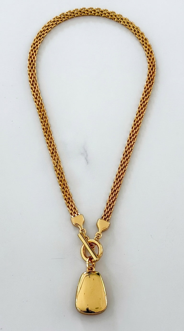Envy gold double mesh chain necklace with front T-bar toggle clasp and polished gold pebble pendant on marble background