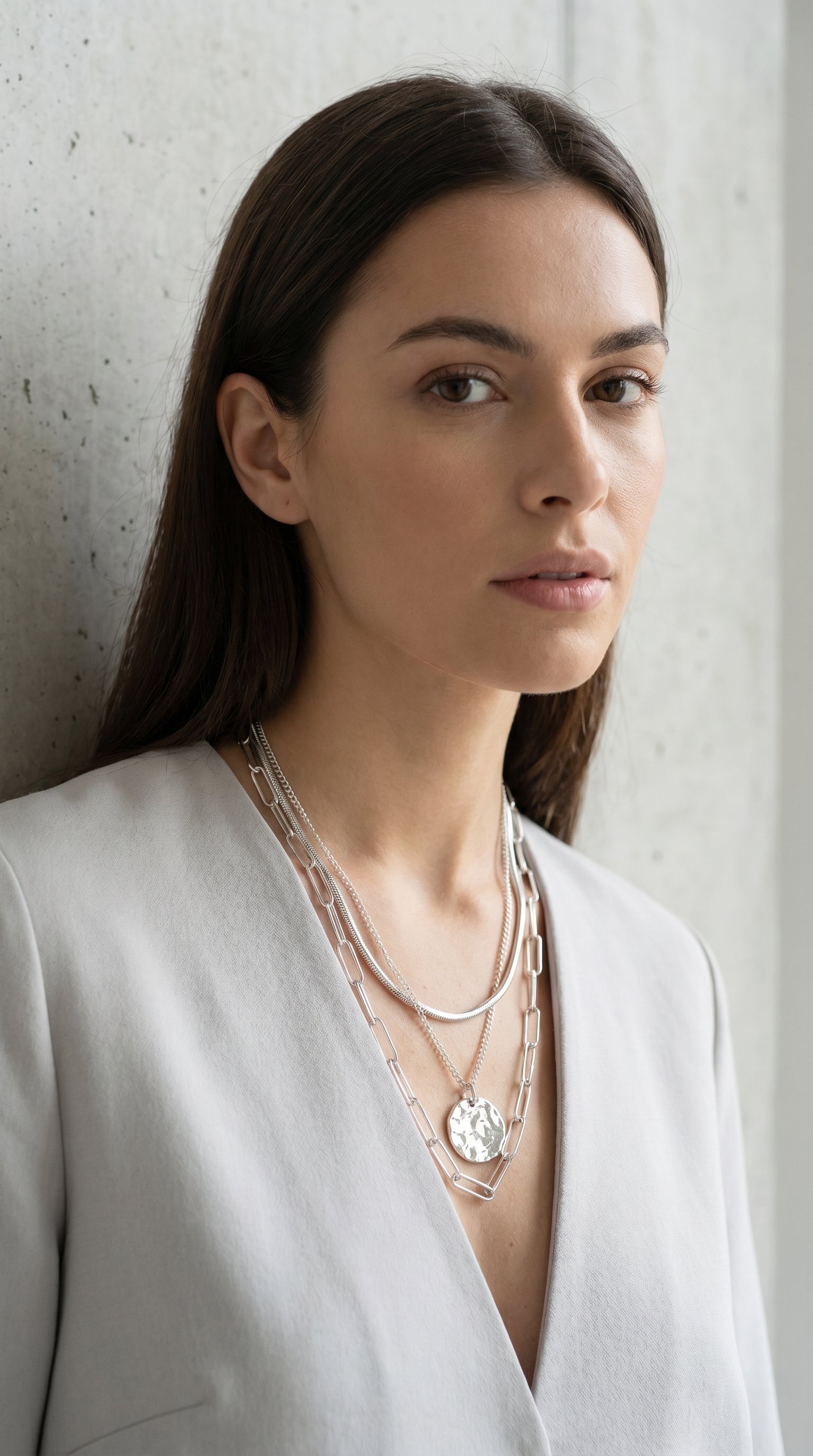 Model wearing Envy silver triple layer snake, curb and paperclip chain coin necklace with white blazer