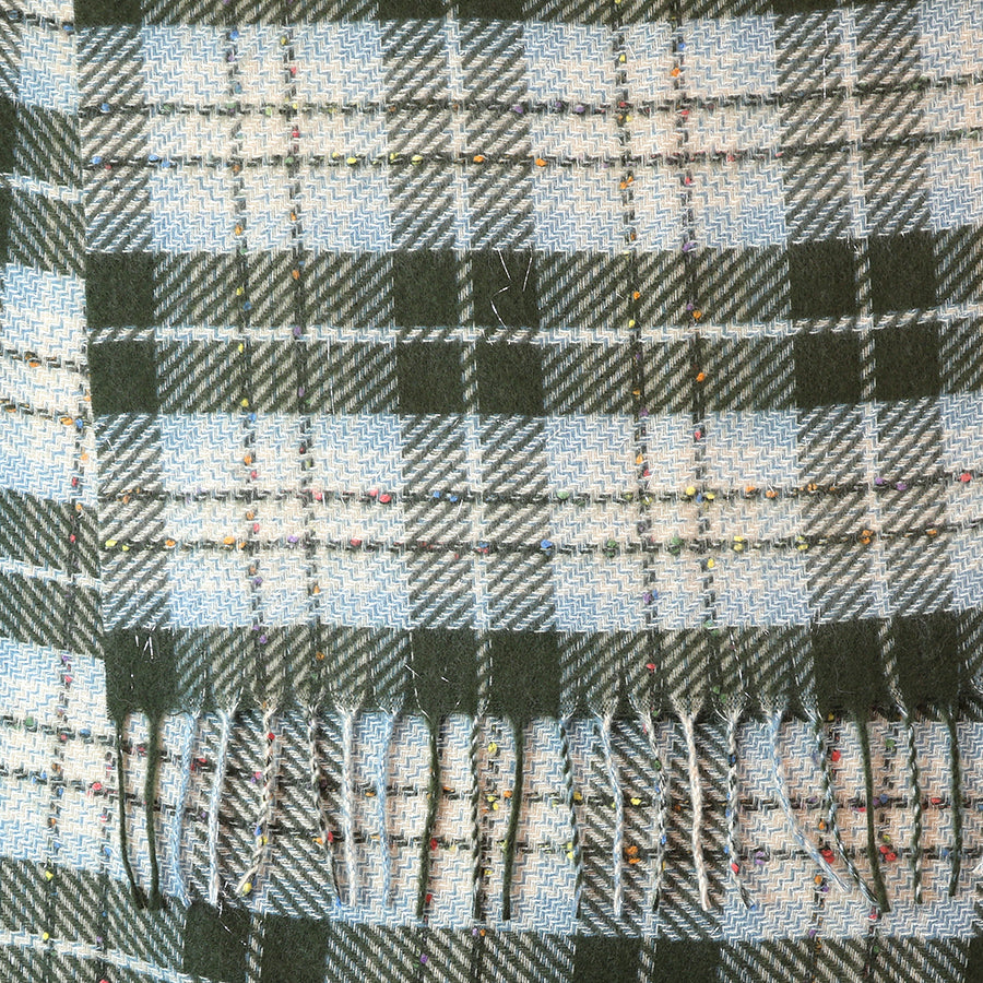 Close-up of the POM Olivia dark khaki mix tartan weave scarf fabric, showing the herringbone-style tartan weave in dark khaki and pale blue-grey with scattered multicolour fleck detail and knotted fringe end at the bottom.