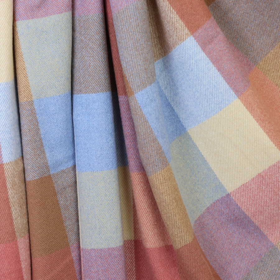 Close-up of the POM Esme blush and blue mix check scarf fabric, showing the oversized block check pattern in blush, periwinkle blue, lilac, camel and cream tones with a soft woven texture.