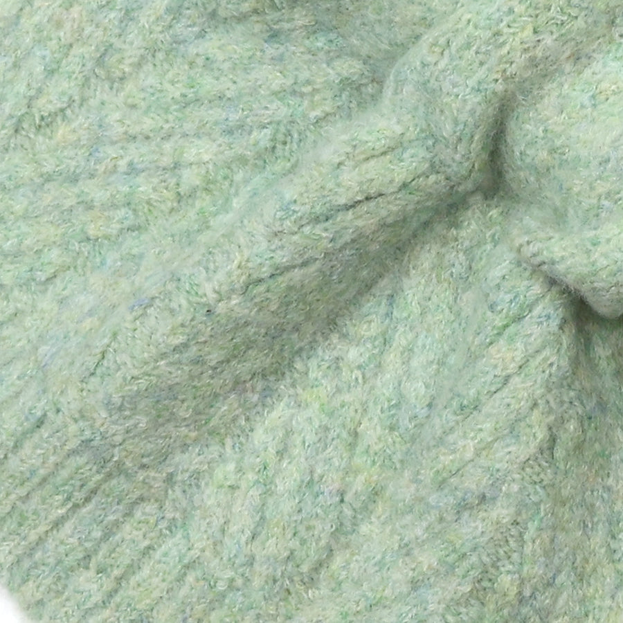 A close-up of a soft, textured knit fabric in a pale mint green color, showing the detailed ribbed and cable-knit patterns.