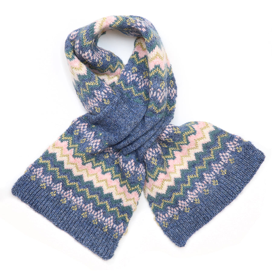 Close-up of the POM Sofia denim, pink and gold Fair Isle pull-through scarf fabric, showing the chevron and diamond Fair Isle pattern in blush pink, teal and shimmering gold metallic thread on a denim blue knit ground with ribbed edge.