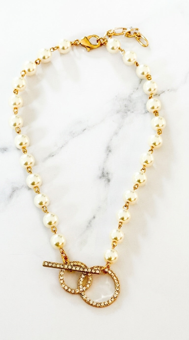 Envy pearl and gold bead necklace with pavé crystal double ring toggle clasp on marble background