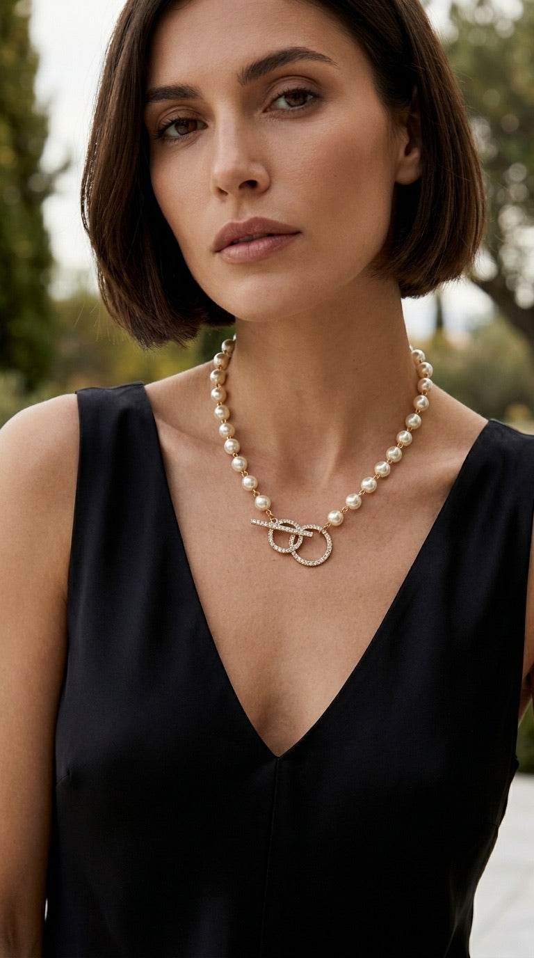 Model wearing Envy pearl and gold bead necklace with pavé double ring toggle with black v-neck dress