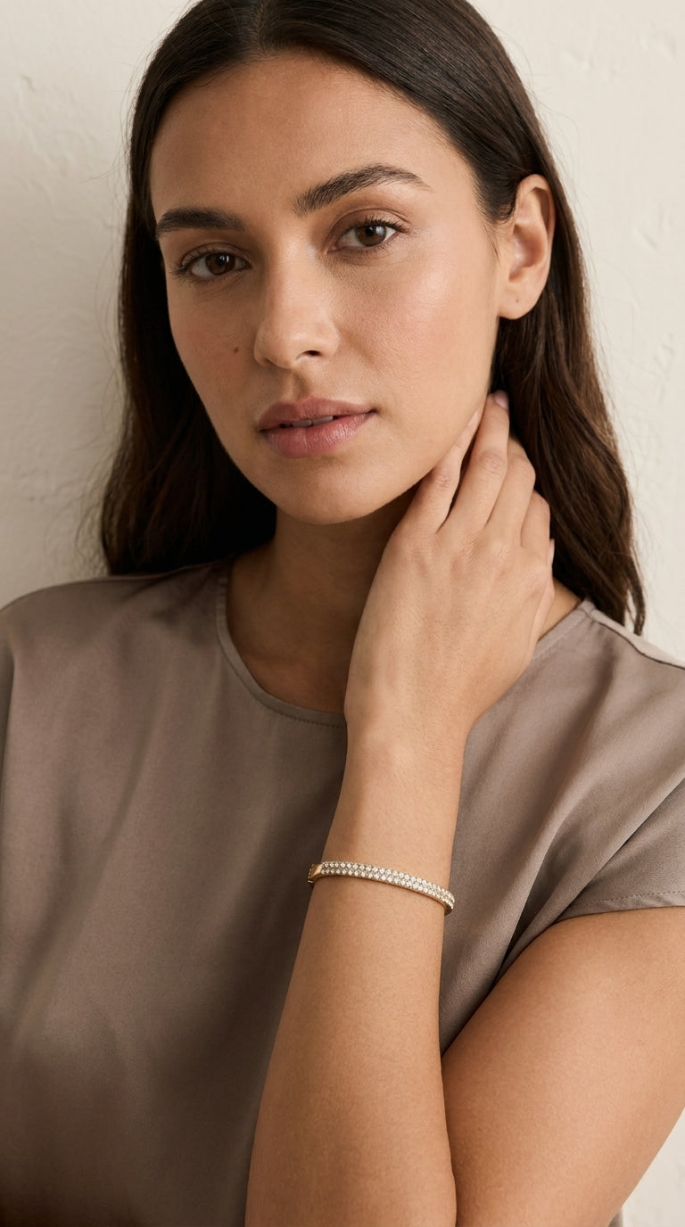 Model wearing Envy gold double row pavé crystal hinged bangle with taupe satin cap sleeve top