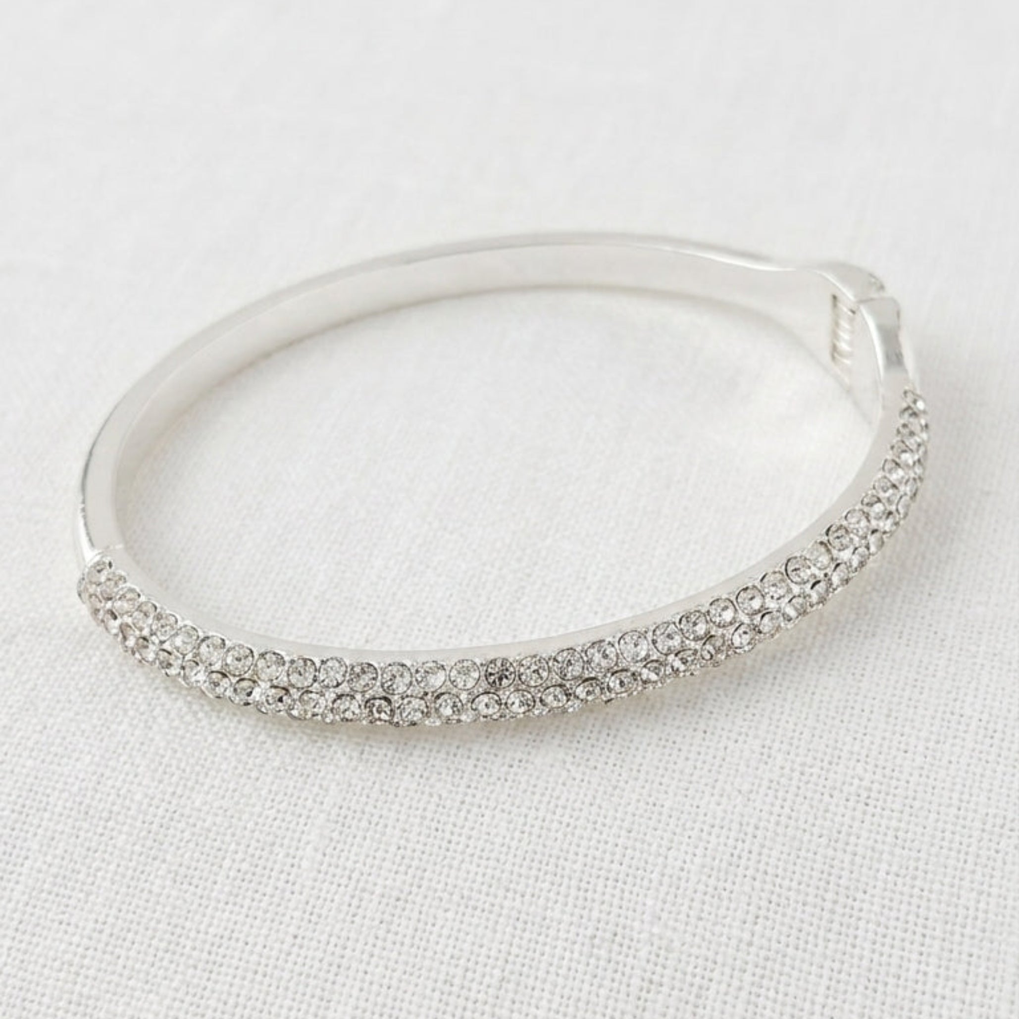 Envy silver hinged bangle with double row pavé crystal front on cream linen background