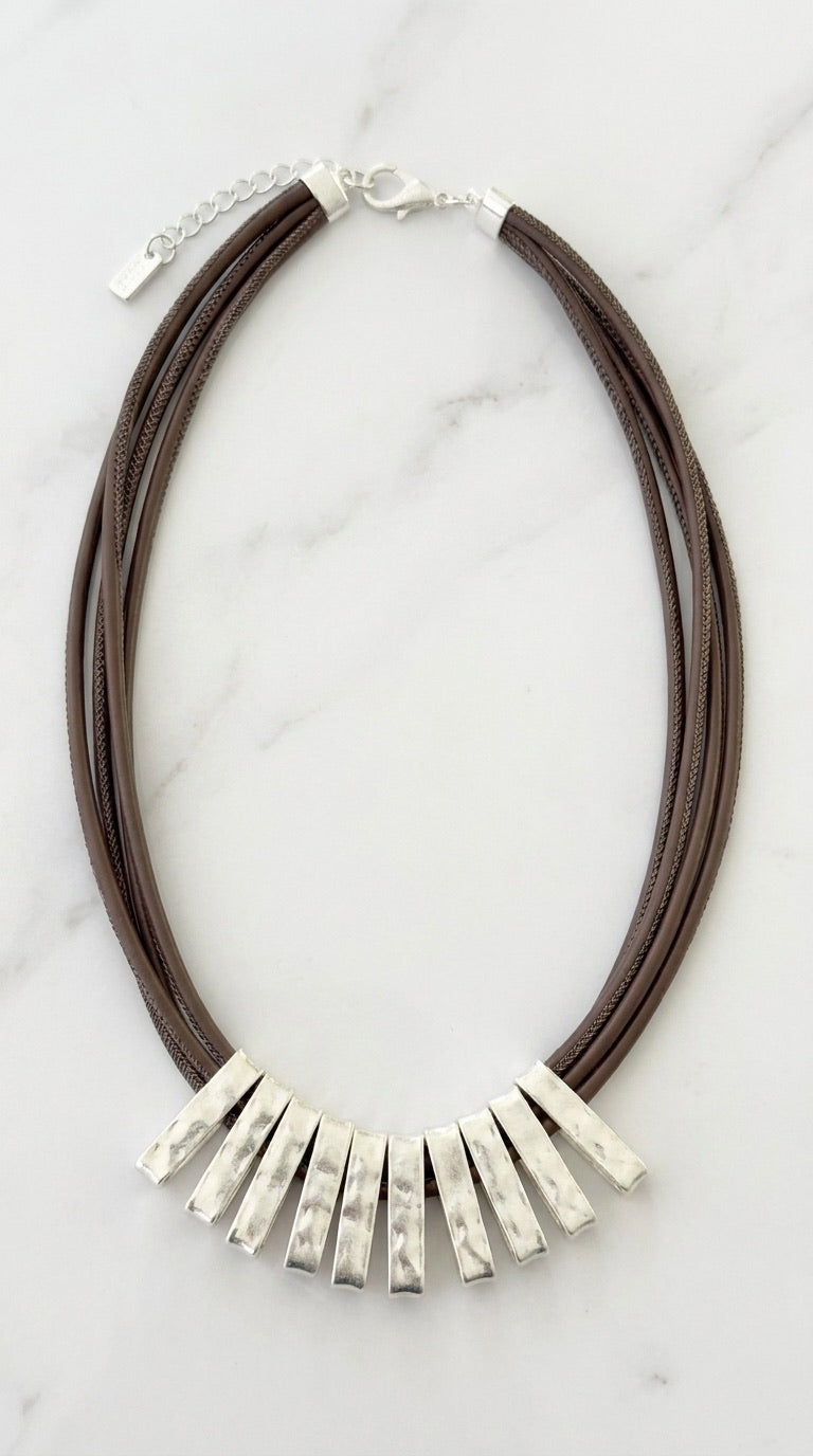 Envy triple brown cord necklace with graduated hammered silver bar tube fan bib on marble background