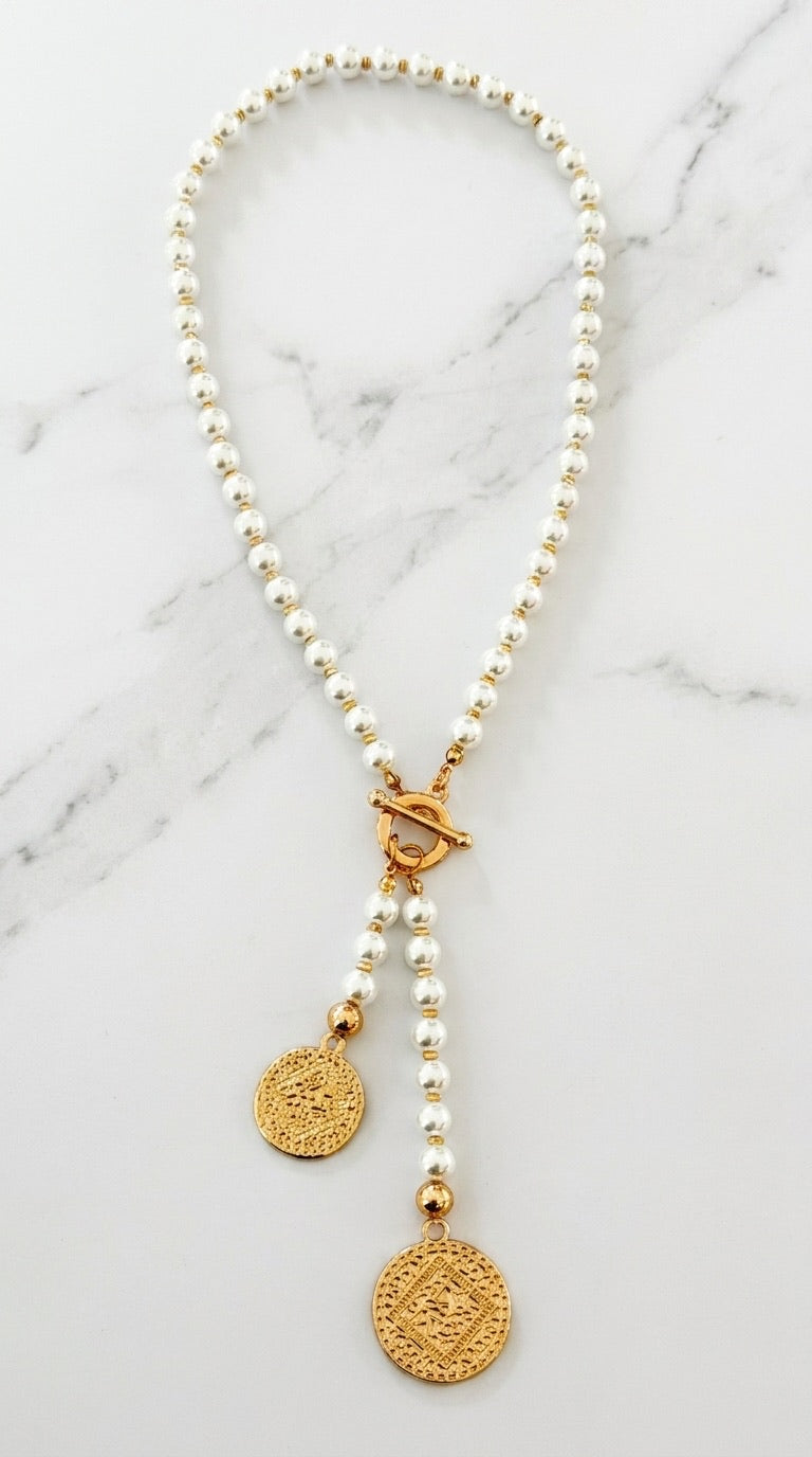 Envy pearl bead necklace with gold rondelle spacers, toggle clasp and two graduated gold coin pendants on marble background