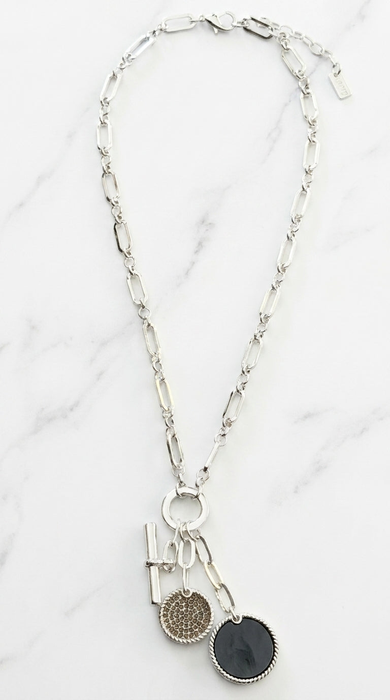 Envy silver mixed link chain necklace with bar, pavé crystal disc, and dark coin charm cluster on marble background