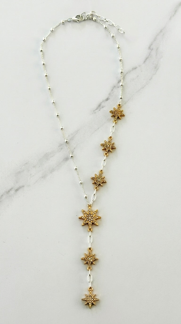Envy two-tone lariat necklace with six graduated gold pavé crystal star charms on marble background