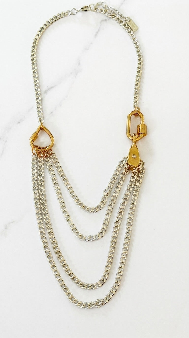 Envy two-tone necklace with four draped silver curb chains and gold carabiner connectors on marble background