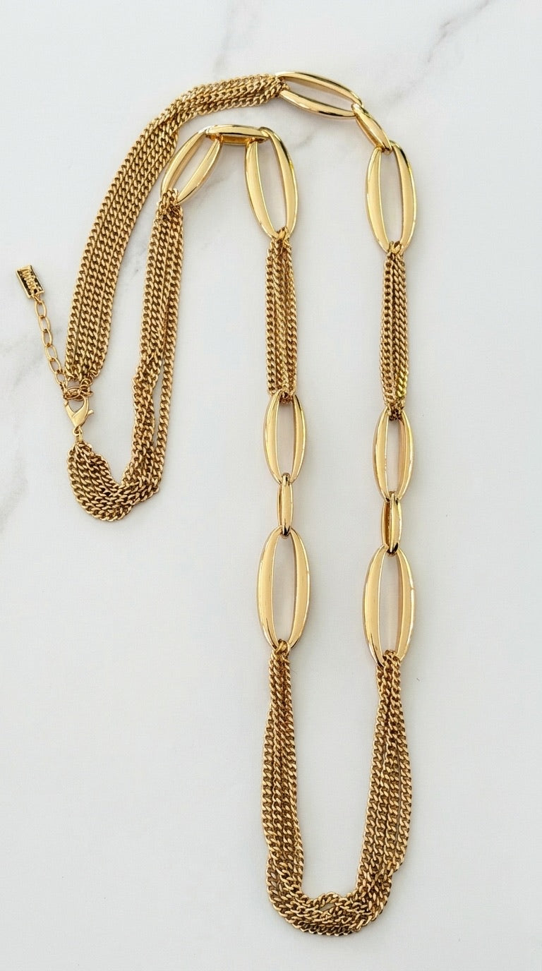 Envy gold long necklace with oversized oval links and fine multi-strand curb chains on marble background