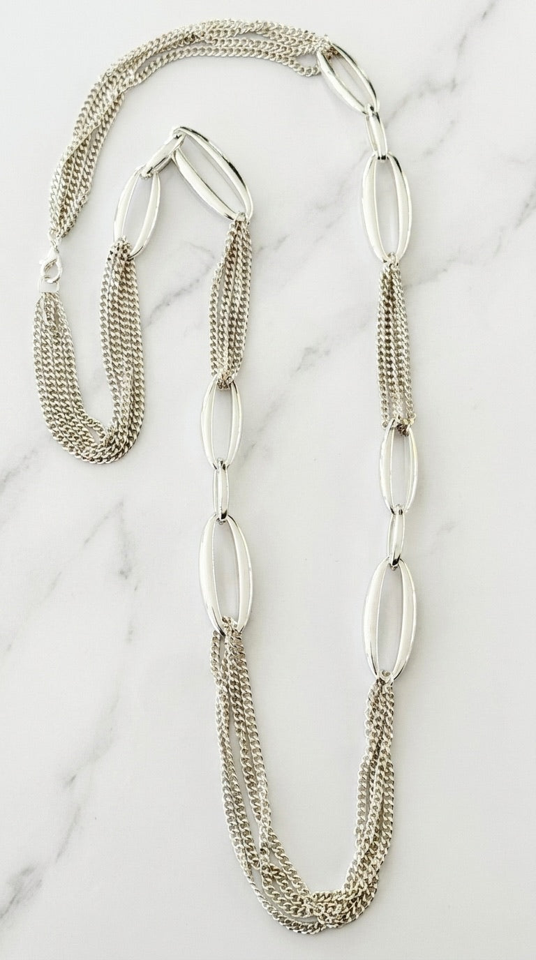 Envy silver long necklace with oversized oval links and fine multi-strand curb chains on marble background