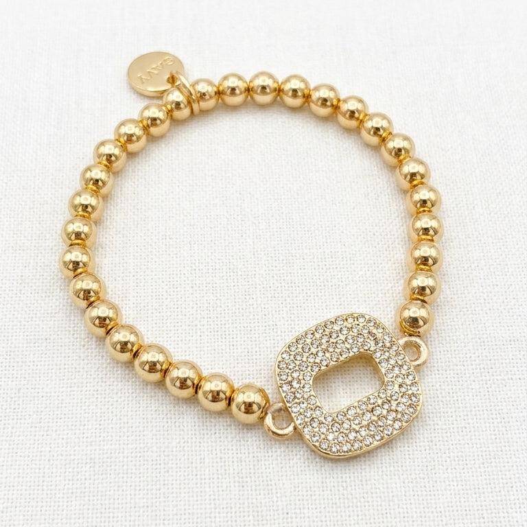 Envy gold ball bead stretch bracelet with fully pavé crystal open oval link centrepiece on white linen background