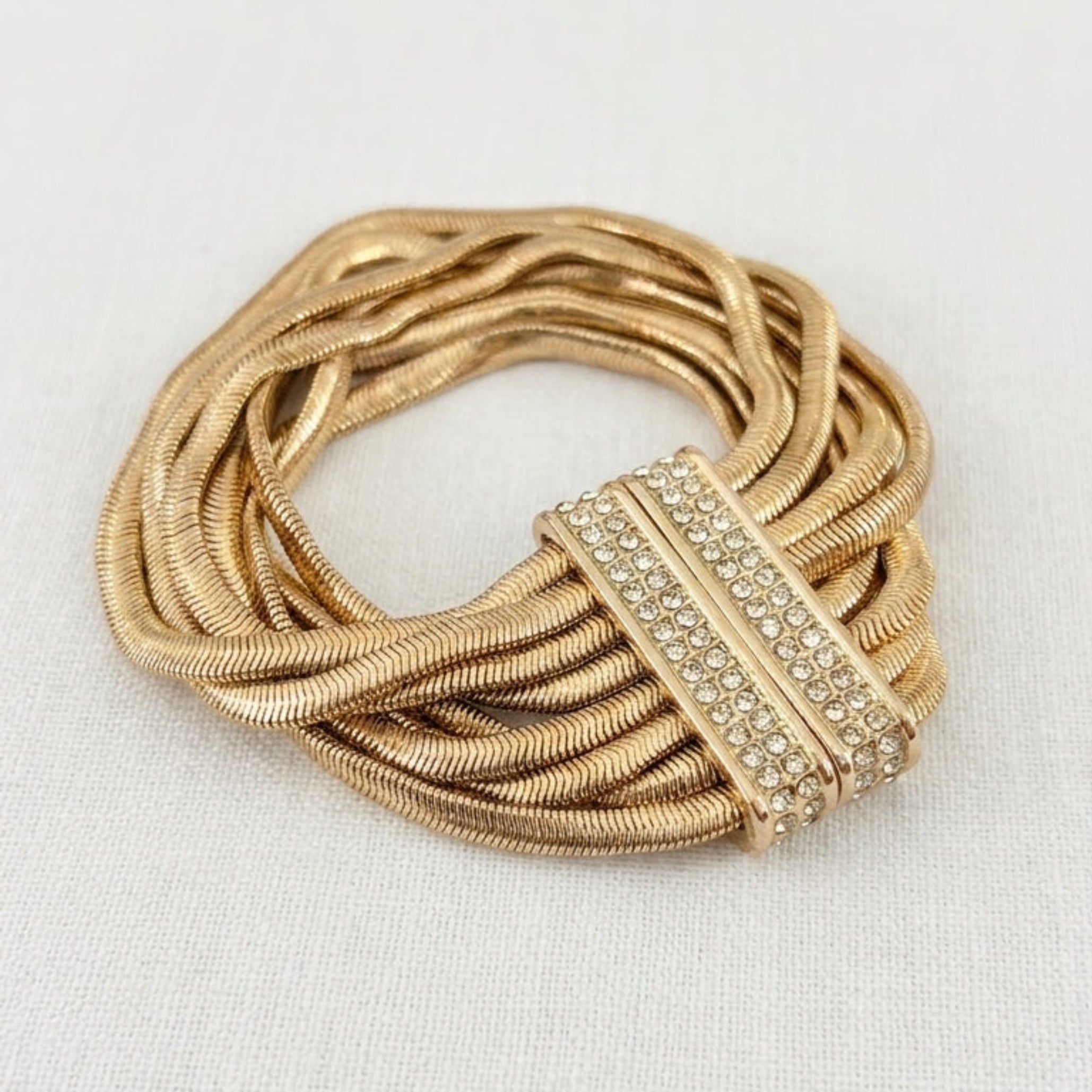 Envy gold multi-strand snake chain bracelet with pavé crystal magnetic bar clasp on cream linen background