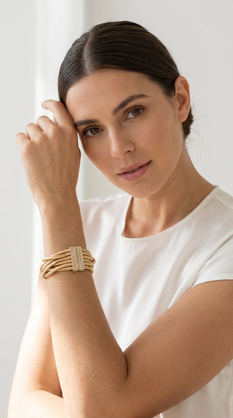 Model wearing Envy gold multi-strand snake chain bracelet with pavé crystal magnetic clasp with white cap sleeve top