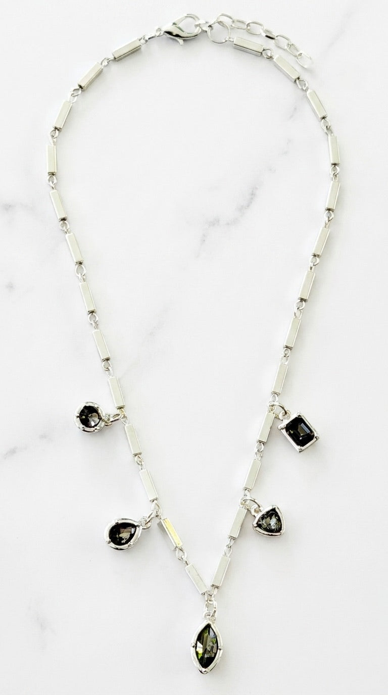Envy silver bar-link necklace with dark smoky mixed-cut crystal charms on marble background