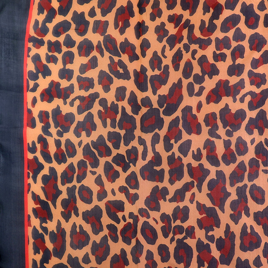 Close-up of the POM camel and navy leopard print silk scarf fabric, showing the rich camel, burgundy-red and navy leopard print pattern and lightweight silk texture with red border stripe.