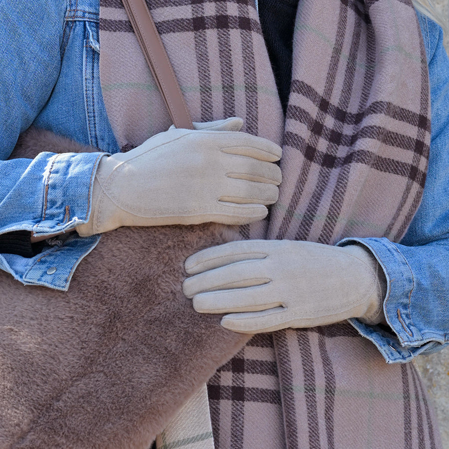Model wearing POM Kate stone faux suede gloves, styled with a denim jacket and pink check scarf, hands resting on a camel coat.