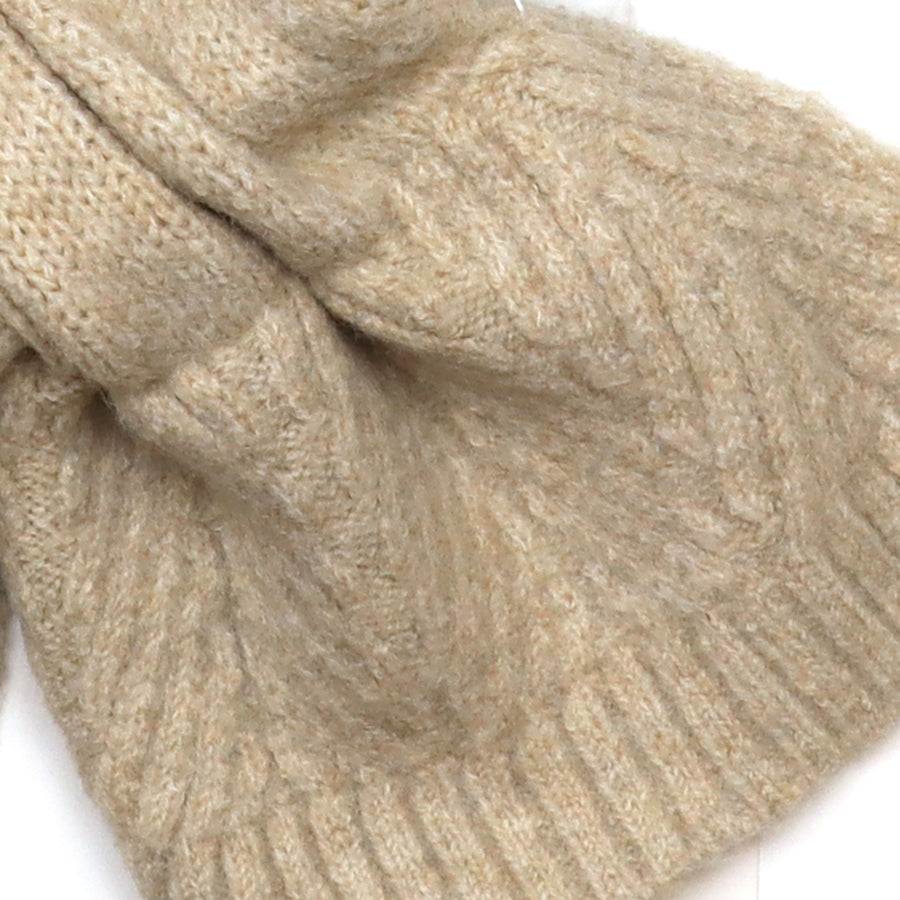 Close-up of the POM Charlotte oatmeal pull-through scarf fabric, showing the soft cable and herringbone knit texture in warm oatmeal tones.