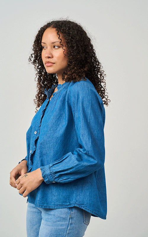 Woman wearing Luella Brora soft cotton denim blouse with frilled collar and button cuffs