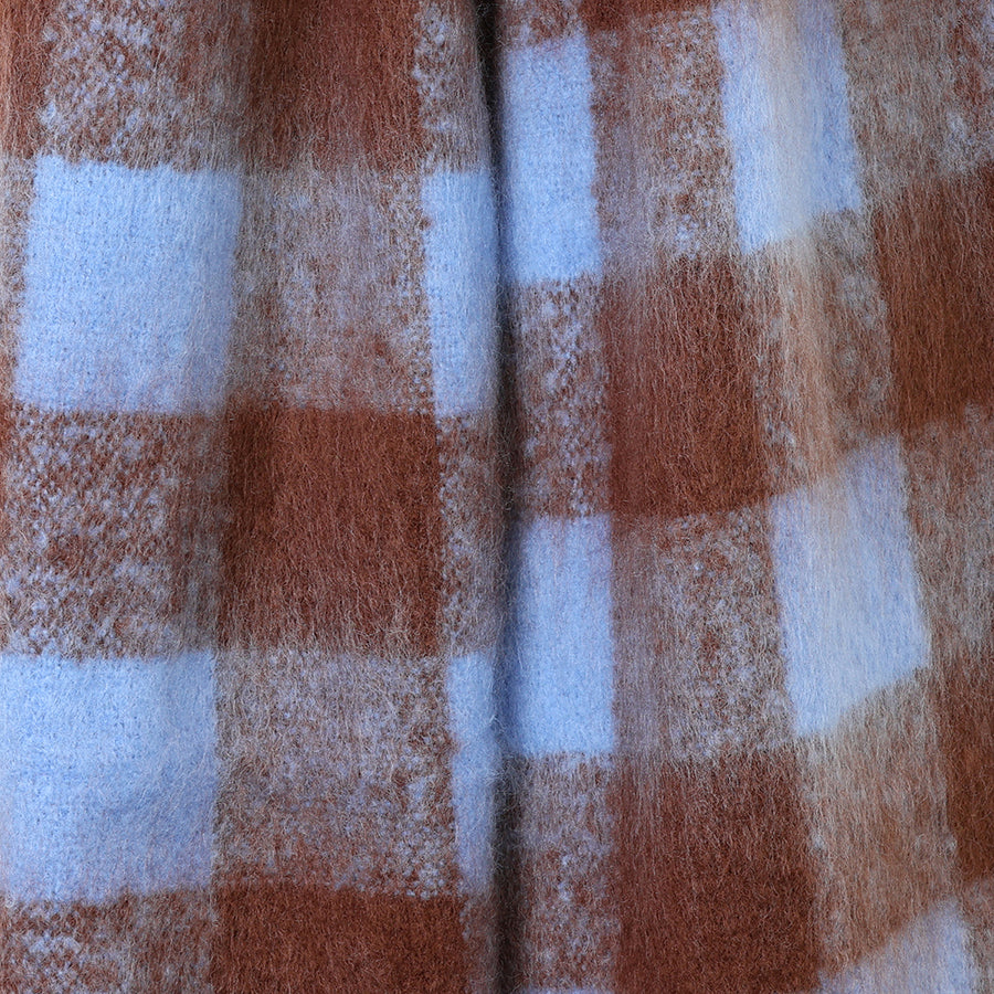 Close-up of the POM Molly scarf fabric, showing the soft fluffy texture of the bold brown and cornflower blue check pattern.
