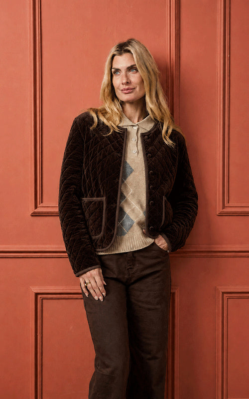 Woman wearing Luella chocolate brown quilted velvet reversible jacket styled over an argyle knit jumper