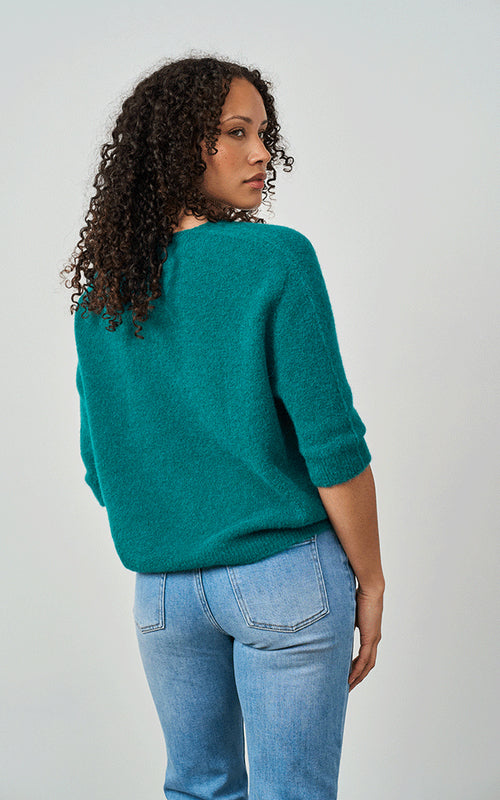 Woman wearing Luella Valentina teal alpaca short-sleeve V-neck knit jumper with blue jeans