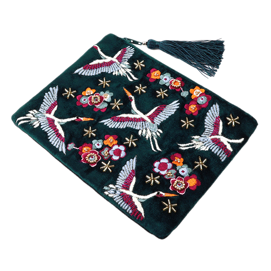 POM Crane teal velvet clutch purse hand-embroidered with soaring cranes, red and orange blooms and gold star beads on deep teal velvet, with a matching teal tassel zip pull, shown against a white background.
